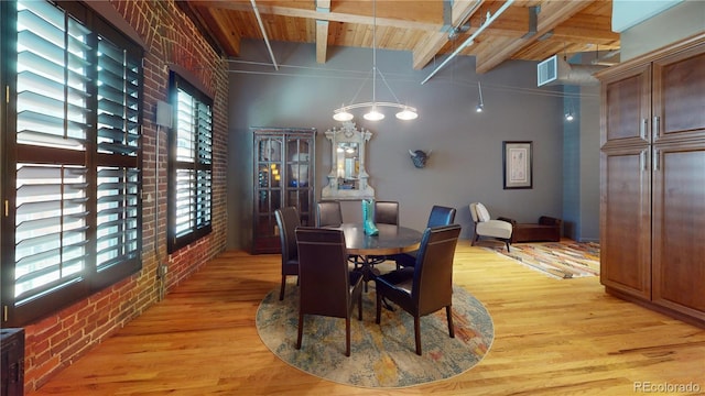 1745 Wazee St Unit 4H, Denver, CO 80202 - dining area featuring brick wall, light wood finished floors, beam ceiling, and a chandelier