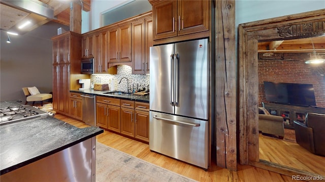 1745 Wazee St Unit 4H, Denver, CO 80202 - kitchen featuring stainless steel appliances, dark countertops, light wood-style floors, tasteful backsplash, and brown cabinets