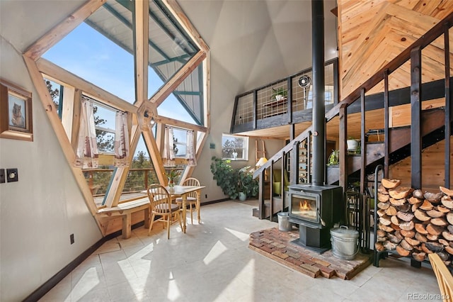 interior space with a wood stove, baseboards, and a high ceiling