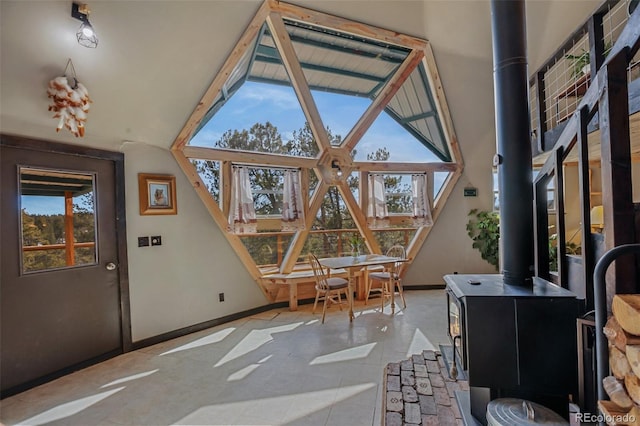 interior space with lofted ceiling, a wood stove, and a healthy amount of sunlight