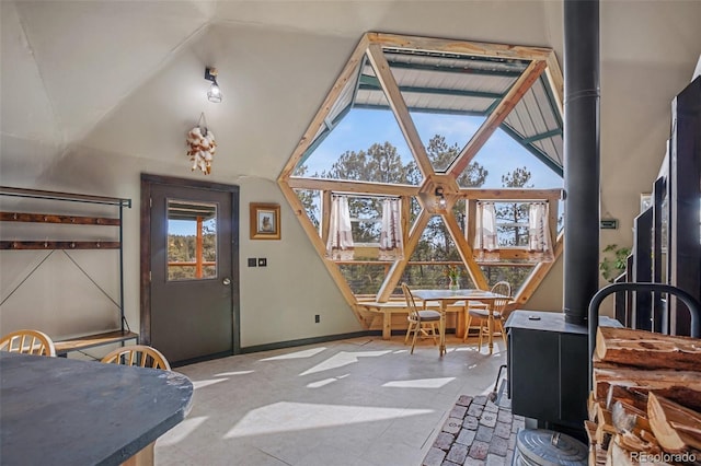 interior space with a wood stove, vaulted ceiling, and baseboards