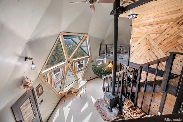 interior space featuring wooden walls, a towering ceiling, and a ceiling fan