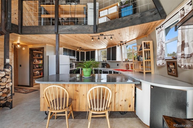 kitchen featuring a breakfast bar area, wooden ceiling, a sink, freestanding refrigerator, and track lighting