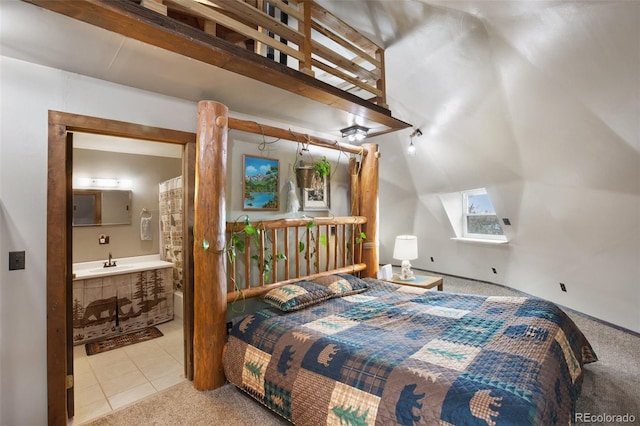 carpeted bedroom with vaulted ceiling, a sink, and ensuite bath