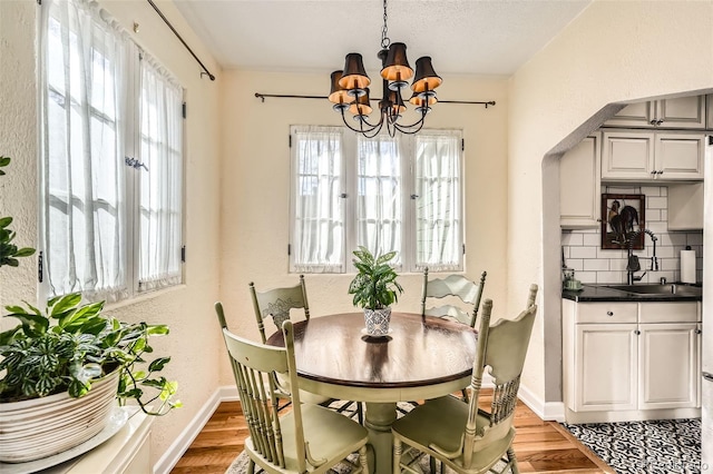 dining area featuring a healthy amount of sunlight, baseboards, light wood finished floors, and a chandelier