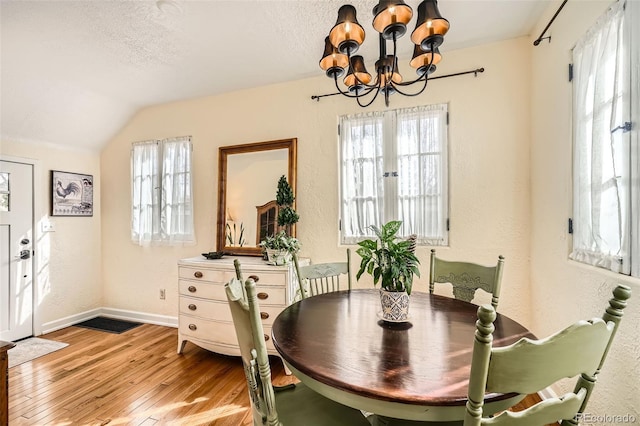 dining room featuring a chandelier, a healthy amount of sunlight, a textured ceiling, and wood finished floors