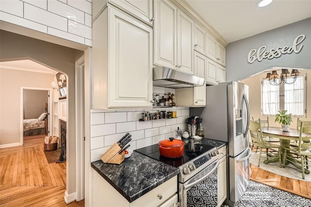 kitchen with light wood finished floors, electric range, under cabinet range hood, a notable chandelier, and backsplash