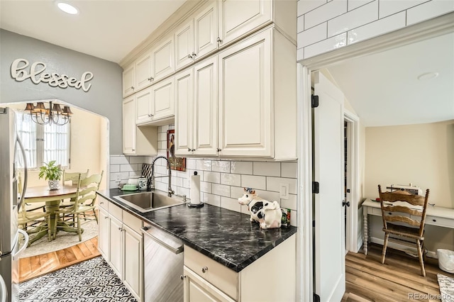 kitchen featuring a sink, stainless steel appliances, dark countertops, and an inviting chandelier