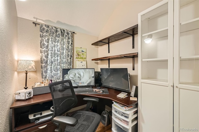 office area featuring a textured wall and vaulted ceiling