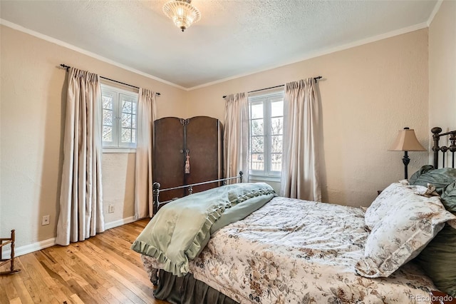 bedroom with a textured ceiling, crown molding, baseboards, and wood finished floors