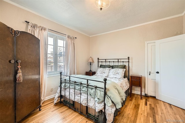 bedroom with hardwood / wood-style floors, ornamental molding, baseboards, and a textured ceiling