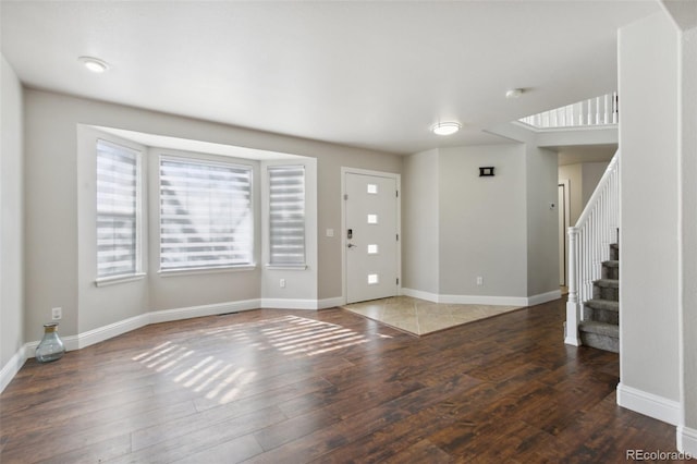 foyer entrance with stairs, baseboards, and wood finished floors