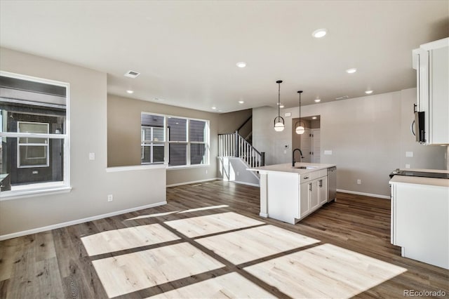 kitchen with white cabinetry, sink, dark hardwood / wood-style floors, decorative light fixtures, and a kitchen island with sink