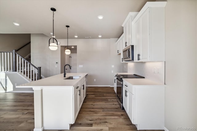 kitchen with white cabinets, sink, an island with sink, and black / electric stove