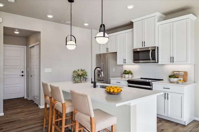 kitchen with white cabinets, stainless steel appliances, hanging light fixtures, and a breakfast bar area