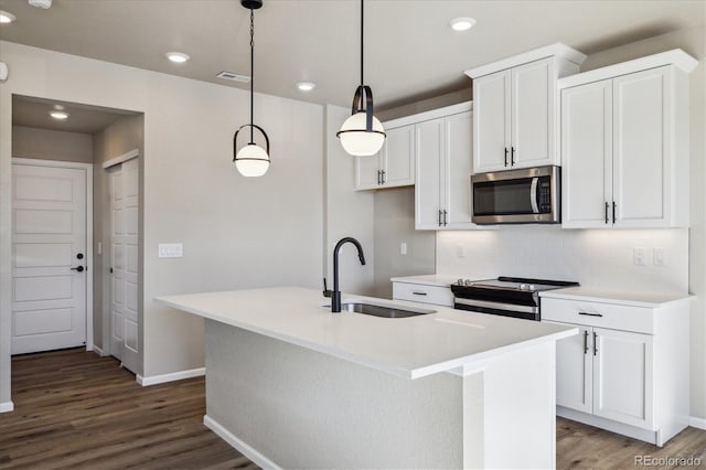 kitchen featuring sink, electric range oven, wood-type flooring, decorative light fixtures, and a center island with sink