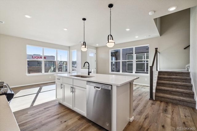 kitchen with white cabinets, sink, decorative light fixtures, a center island with sink, and dishwasher