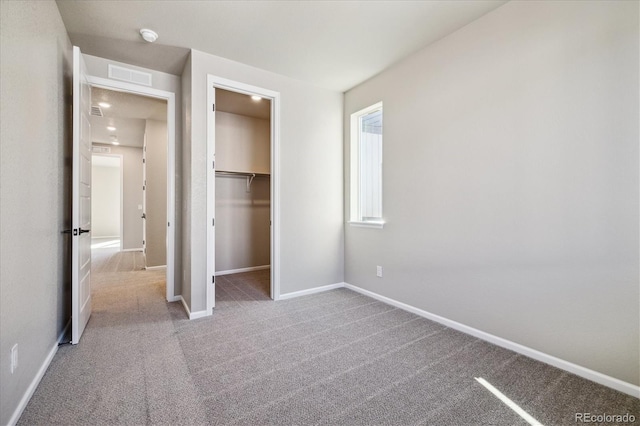 unfurnished bedroom with light colored carpet, a spacious closet, and a closet