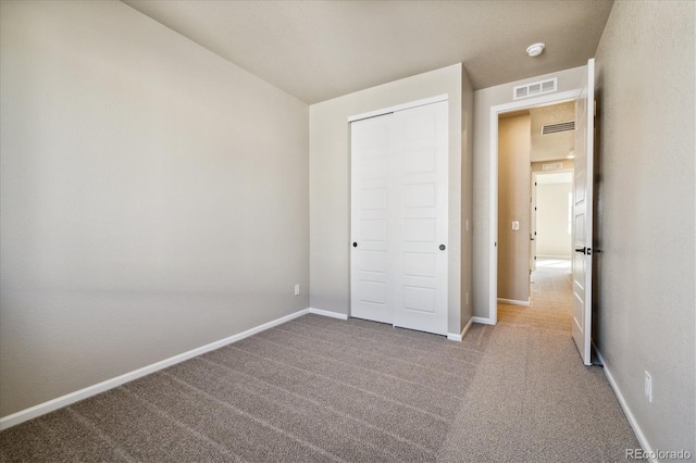 unfurnished bedroom with light colored carpet and a closet