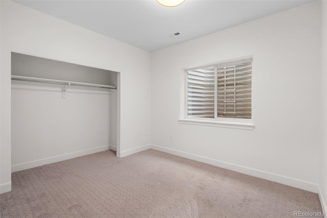 unfurnished bedroom with light colored carpet and a closet