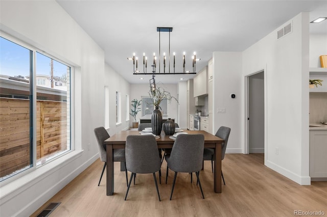 dining room with light hardwood / wood-style flooring and an inviting chandelier