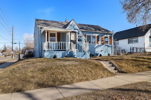 bungalow with covered porch, a chimney, and a front lawn