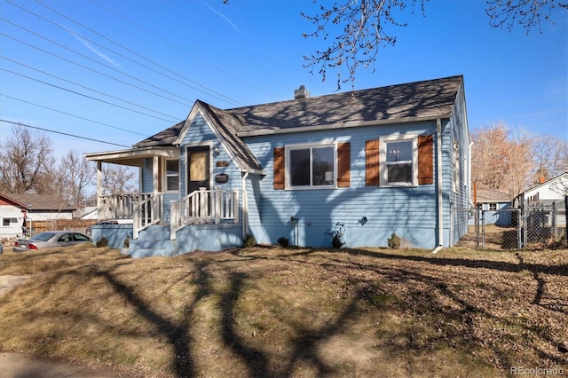 view of front of house featuring covered porch, a chimney, and fence