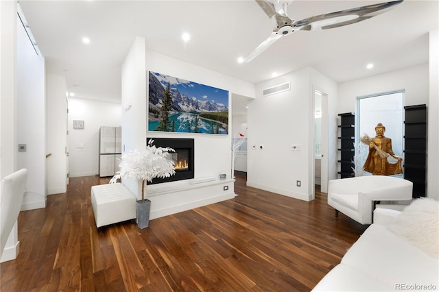 living room featuring ceiling fan and dark wood-type flooring