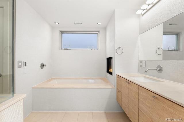 bathroom featuring tile patterned flooring, vanity, and shower with separate bathtub