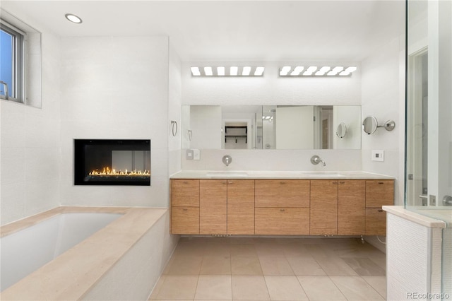 bathroom featuring a relaxing tiled tub, vanity, and tile patterned flooring