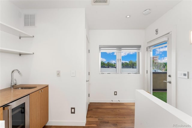 interior space with dark wood-type flooring, sink, and beverage cooler