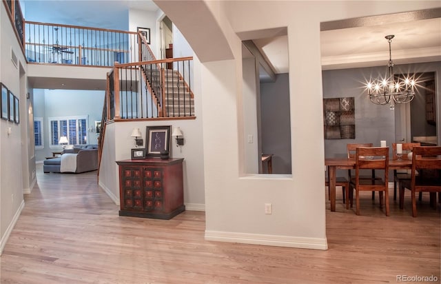 corridor featuring a high ceiling, hardwood / wood-style floors, and a notable chandelier