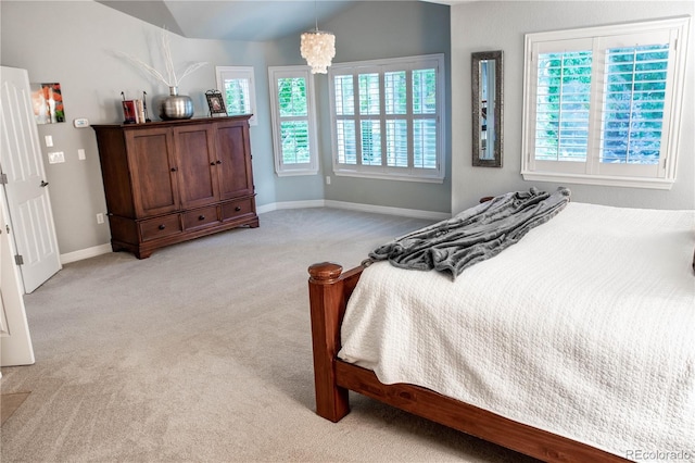 bedroom featuring lofted ceiling, light carpet, and an inviting chandelier