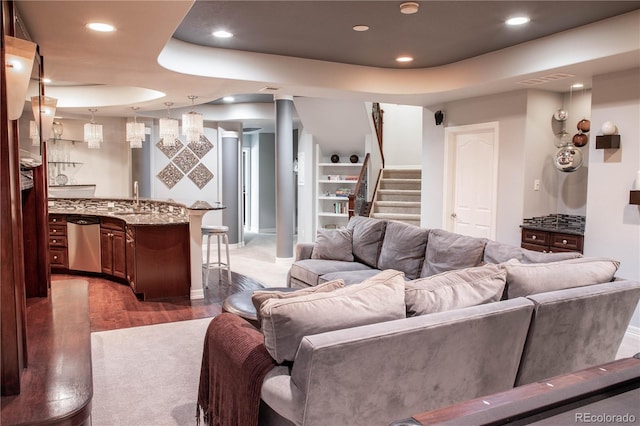 living room featuring a tray ceiling, dark wood-type flooring, and wet bar