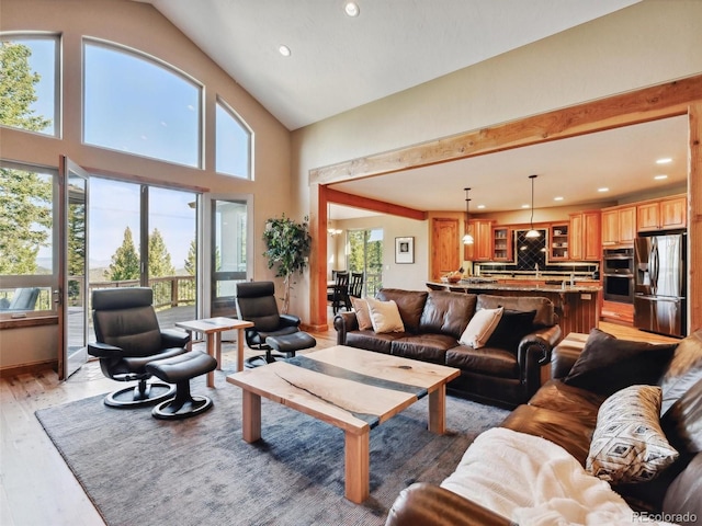 living area with recessed lighting, light wood-type flooring, and high vaulted ceiling