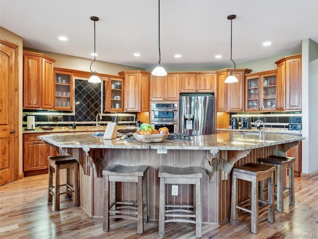 kitchen with stainless steel appliances, brown cabinets, a large island, and decorative backsplash