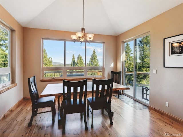 dining room featuring vaulted ceiling, wood finished floors, baseboards, and a chandelier