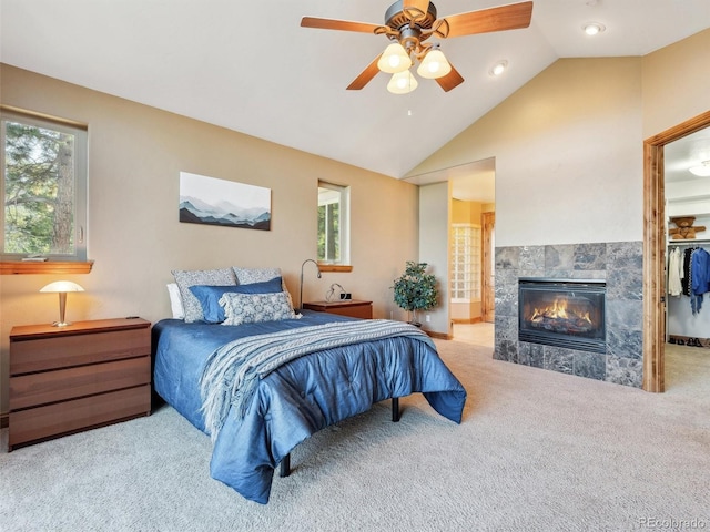 bedroom with carpet floors, lofted ceiling, ensuite bath, ceiling fan, and a tiled fireplace