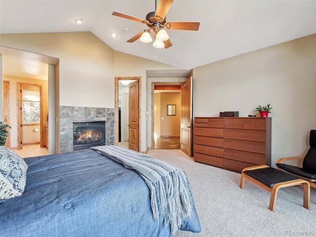 bedroom featuring light carpet, a ceiling fan, a glass covered fireplace, connected bathroom, and lofted ceiling