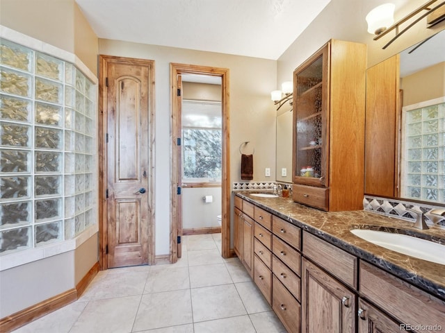 full bathroom with a sink, toilet, double vanity, and tile patterned floors