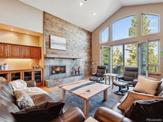 living room featuring recessed lighting, light wood-style floors, high vaulted ceiling, and a tile fireplace