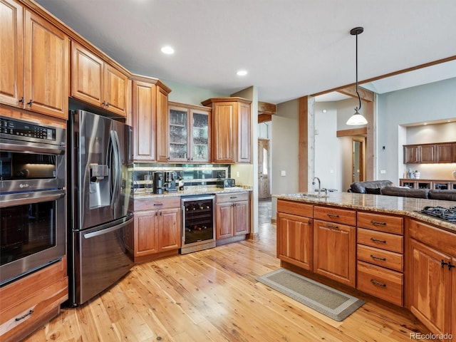 kitchen featuring wine cooler, appliances with stainless steel finishes, brown cabinetry, and light wood finished floors