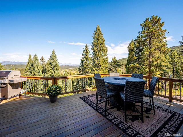 wooden deck with grilling area, a mountain view, a forest view, and outdoor dining area