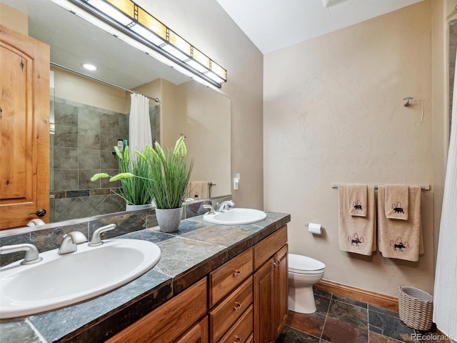 bathroom featuring a sink, baseboards, toilet, and stone tile floors