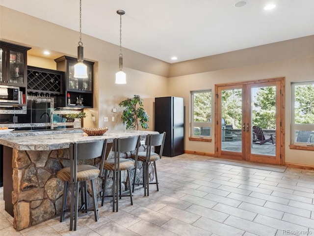 kitchen featuring a breakfast bar, plenty of natural light, light countertops, and freestanding refrigerator