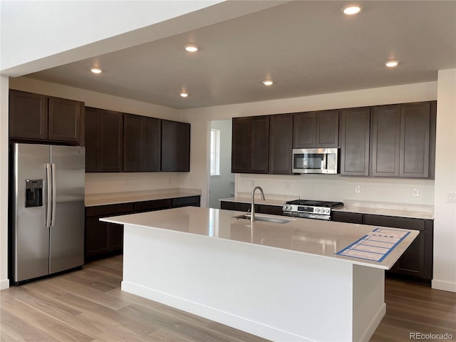 kitchen with dark brown cabinetry, appliances with stainless steel finishes, sink, and a kitchen island with sink