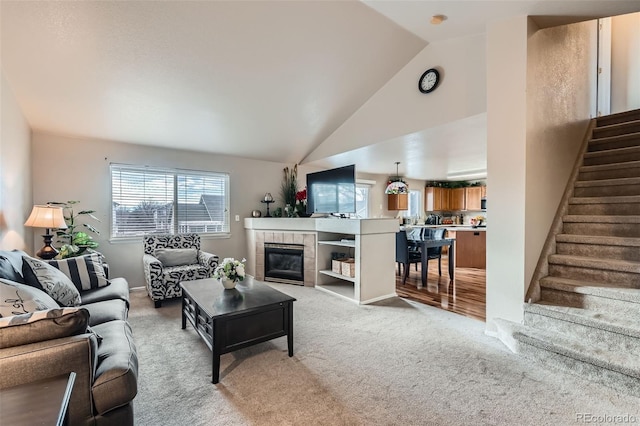 carpeted living room with lofted ceiling and a tile fireplace