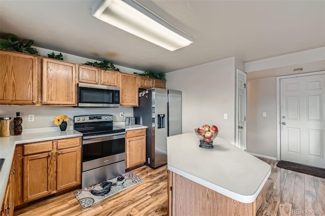 kitchen with a kitchen island, light wood-type flooring, and appliances with stainless steel finishes