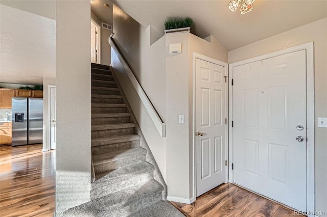 stairway with hardwood / wood-style floors and vaulted ceiling