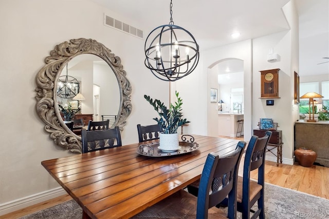 1026 Deer Clover Way, Castle Pines, CO 80108 - dining area featuring arched walkways, a chandelier, wood finished floors, and baseboards